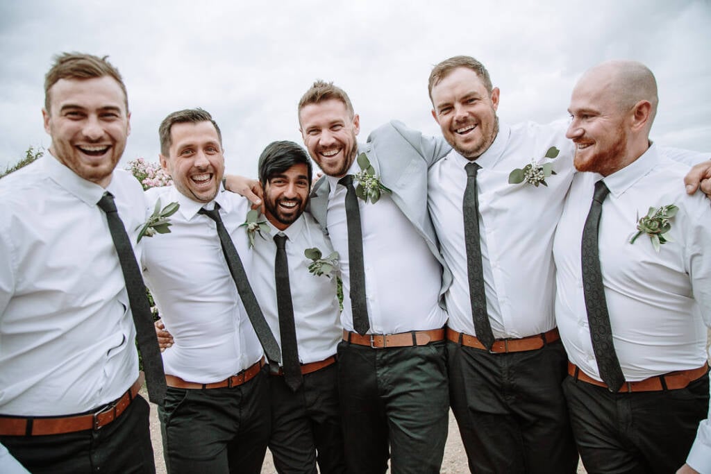 Tory and five attendants stand together in white shirts with succulent boutonnieres.