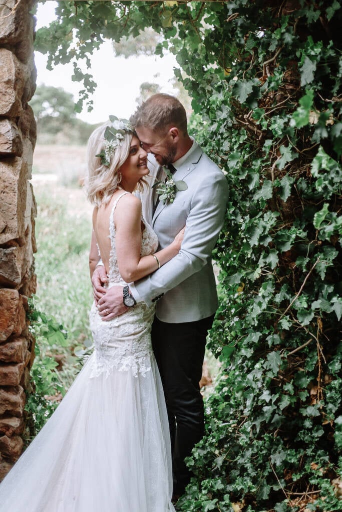 Kelly and Tory touch foreheads in an ivy-framed stone doorway at Camp Sunnystones.