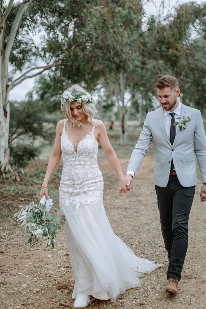Kelly and Tory walk hand in hand along a Merrimu track during their Camp Sunnystones wedding photos.