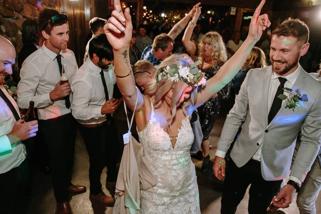 Kelly dances with her arms raised beneath coloured reception lights at Camp Sunnystones.