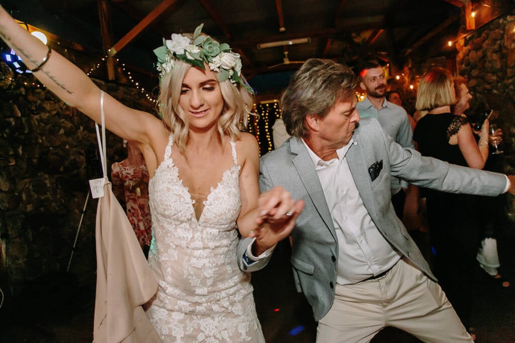 Kelly dances with a guest in a grey jacket at the wedding reception.
