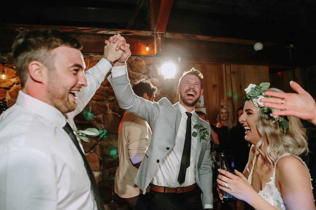 Tory and a wedding attendant clasp hands above their heads while dancing.