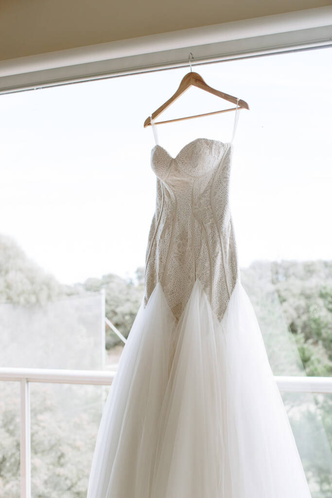 Aasher's lace wedding gown hangs beside a treetop view at her Cape Schanck Airbnb.