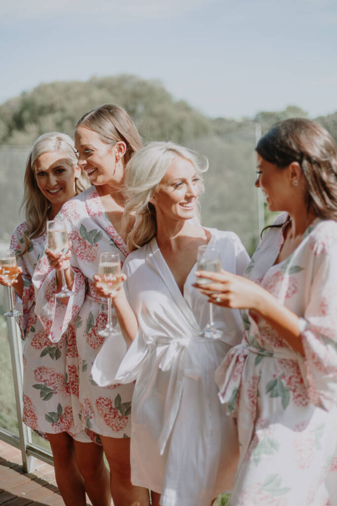 Aasher laughs with three bridesmaids in floral robes on the Cape Schanck Airbnb balcony.