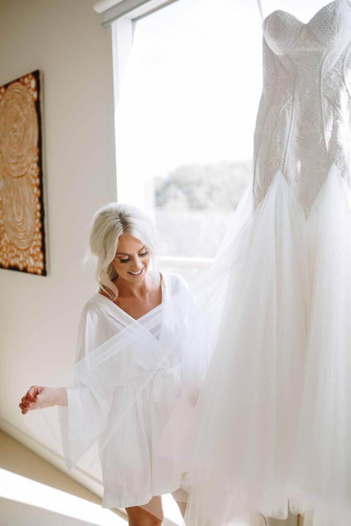 Aasher draws the wide tulle overlay of her gown across the room beneath a dot painting.