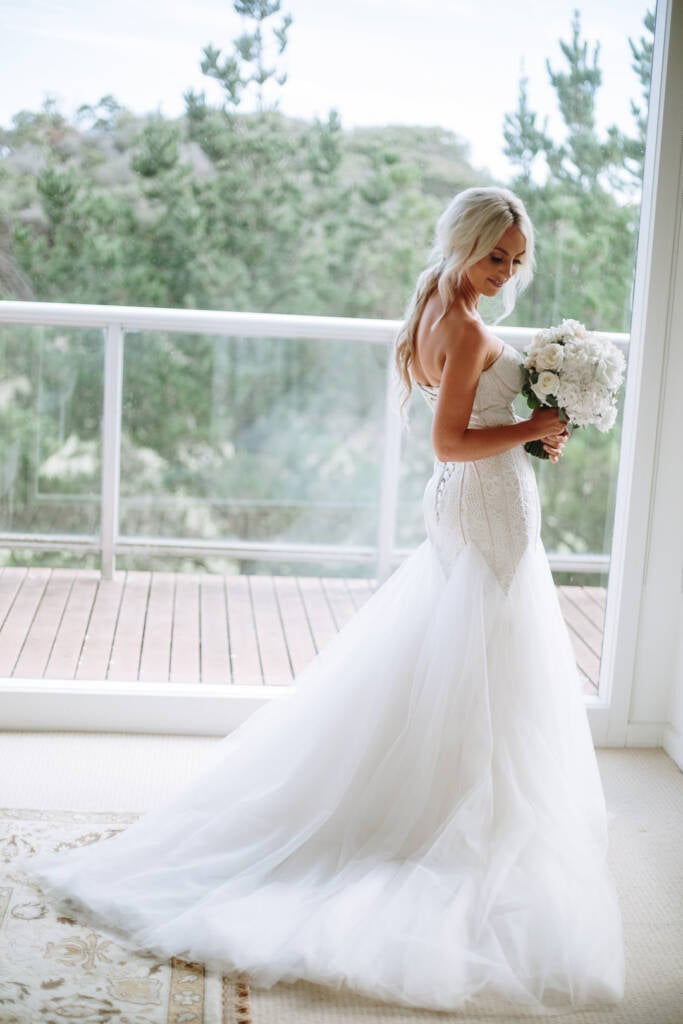 Side on at the balcony doors, Aasher shows the laced back of the mermaid gown to camera.