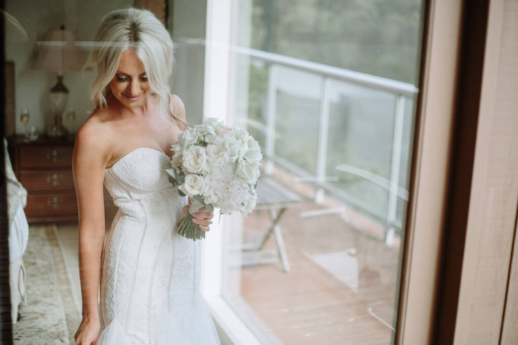 Aasher studies her bouquet through the glass doors of her Cape Schanck Airbnb.
