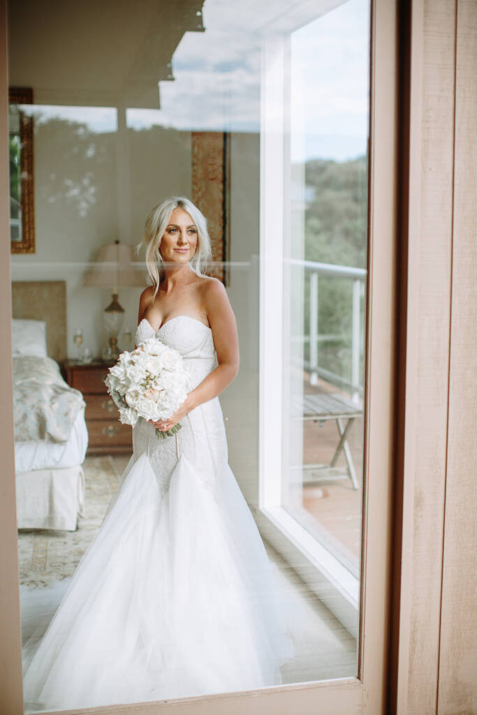 Aasher holds her bouquet beside the reflected balcony at her Cape Schanck Airbnb.