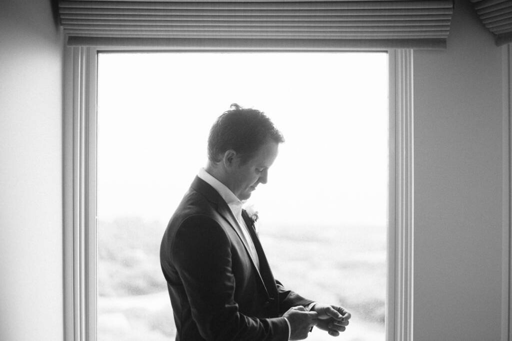 Nick fastens his cuff beside a bright window at RACV Cape Schanck Resort.