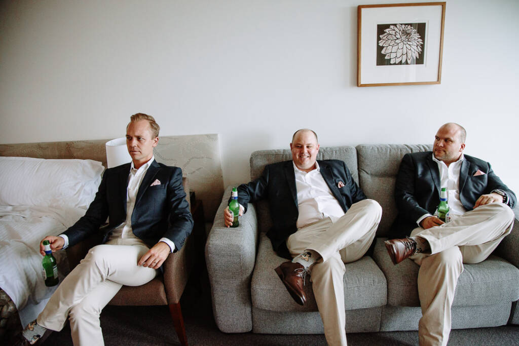 Three groomsmen relax with beers in their room at RACV Cape Schanck Resort.