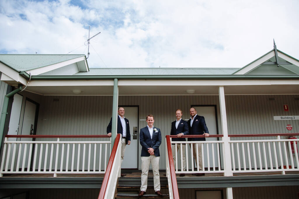 Nick stands with his groomsmen on the timber steps at RACV Cape Schanck Resort.