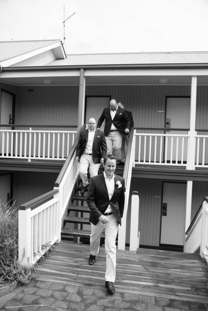 Nick leads three groomsmen down the timber stairs at RACV Cape Schanck Resort.
