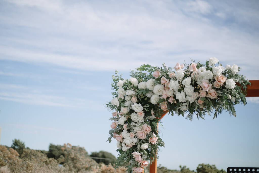 White and blush flowers frame the ceremony arbour at The National Golf Club, Cape Schanck.