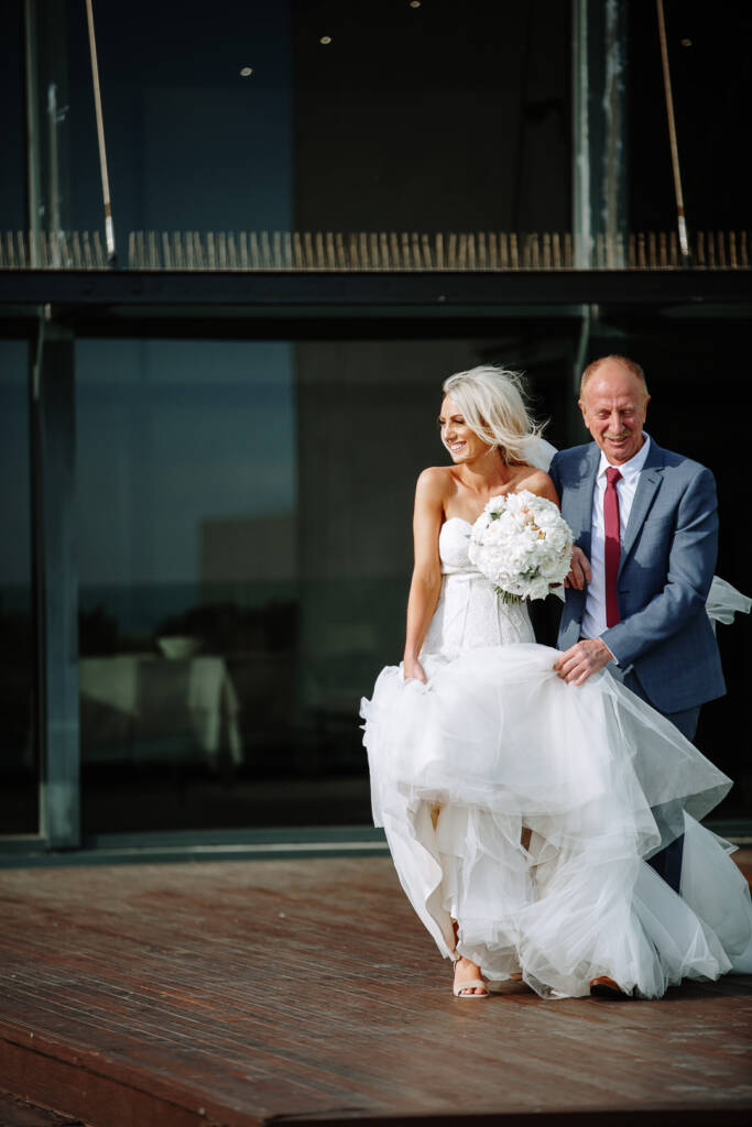 Aasher walks towards The National's terrace ceremony as her escort holds her windblown tulle skirt.