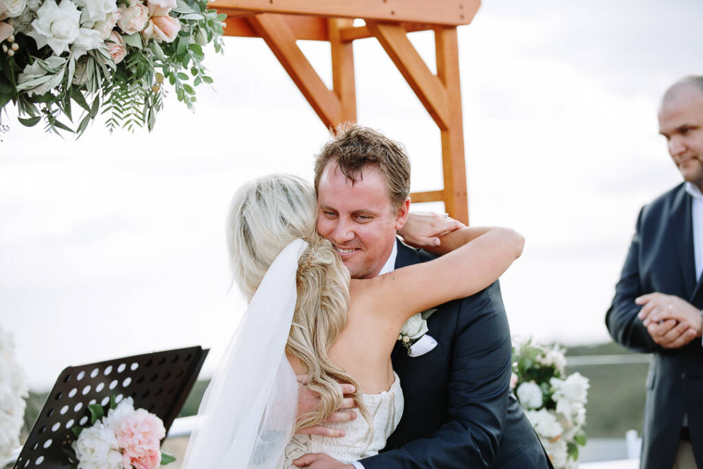 Nick hugs Aasher beneath The National's wedding arbour, smiling through her veil.