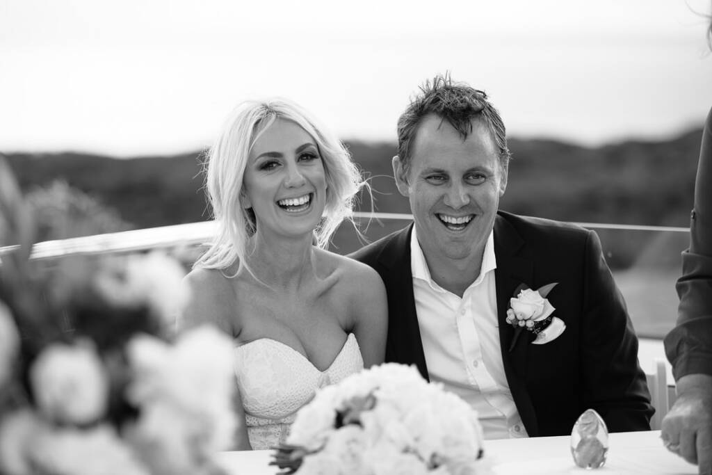 Aasher and Nick smile together at the ceremony table at The National Golf Club.