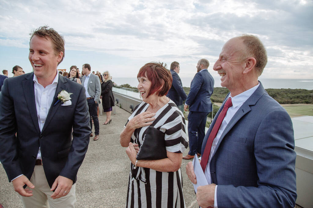 Nick laughs with guests on The National's terrace, with the coastal horizon behind them.