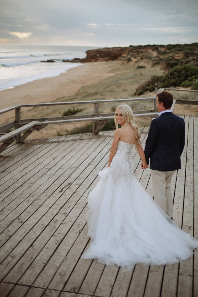 Aasher looks back as Nick leads her along the boardwalk above Fingal Beach.