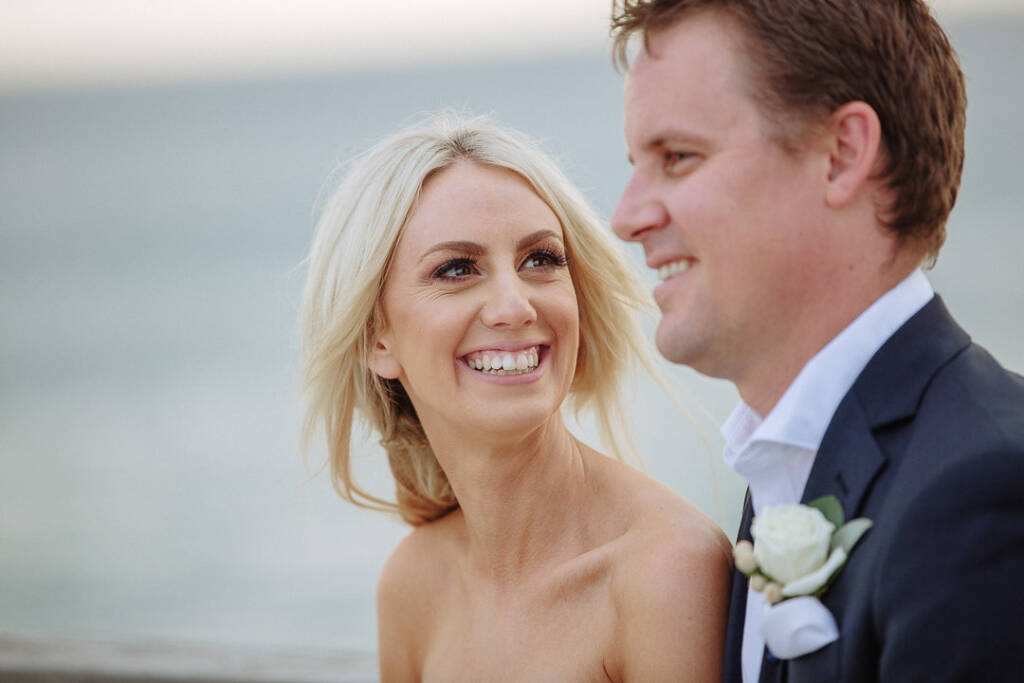 Aasher laughs up at Nick, his white rose boutonniere visible above Fingal Beach.