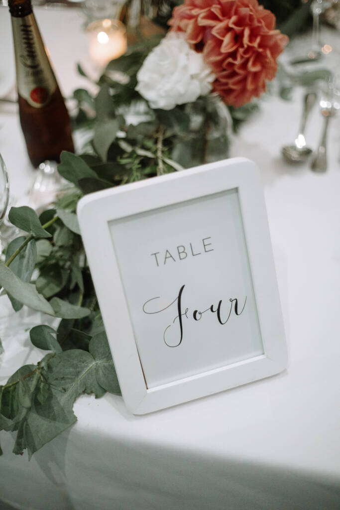 Framed Table Four sign among eucalyptus and roses at The National's wedding reception.