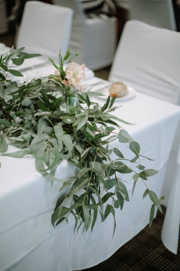 Eucalyptus runner and blush rose on a linen-covered table at The National Golf Club.