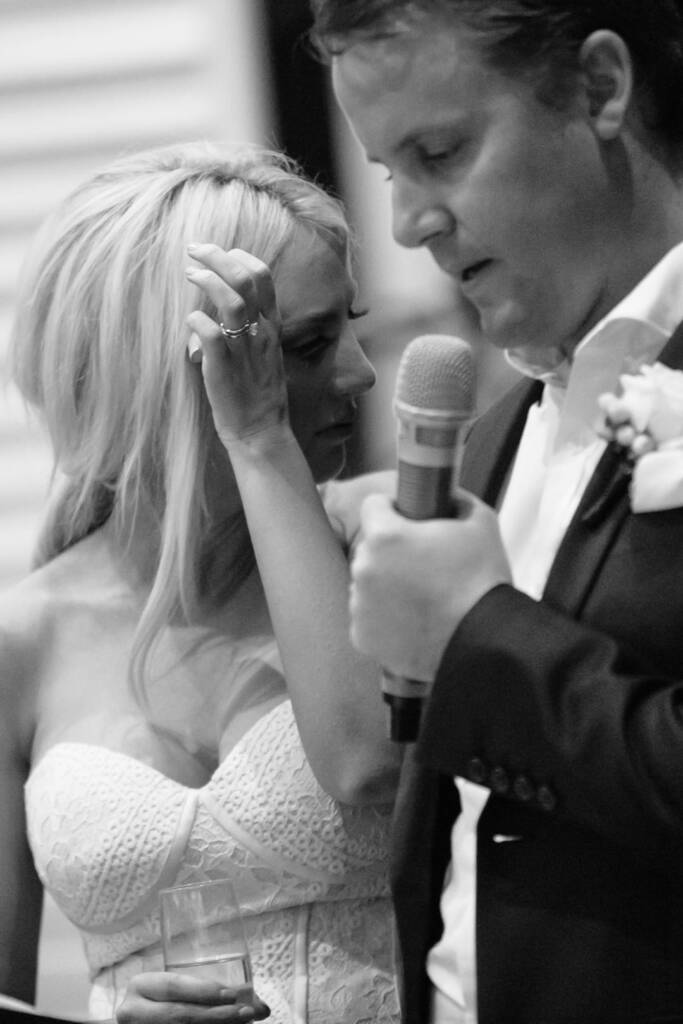 Aasher adjusts her hair as Nick speaks into the microphone at The National's reception.