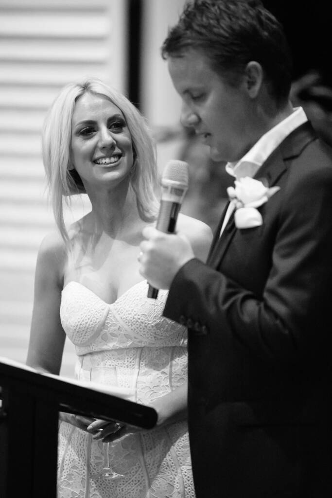 Black and white of Aasher smiling up at Nick as he reads his speech at the lectern.