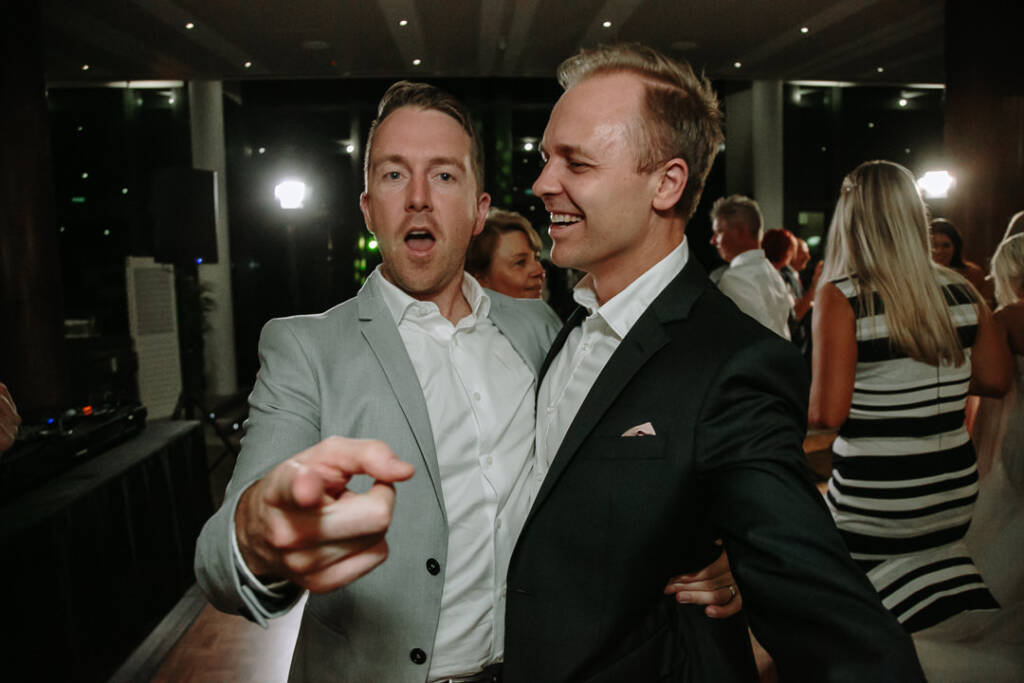 Two guests laugh and point towards the camera on The National's dance floor.