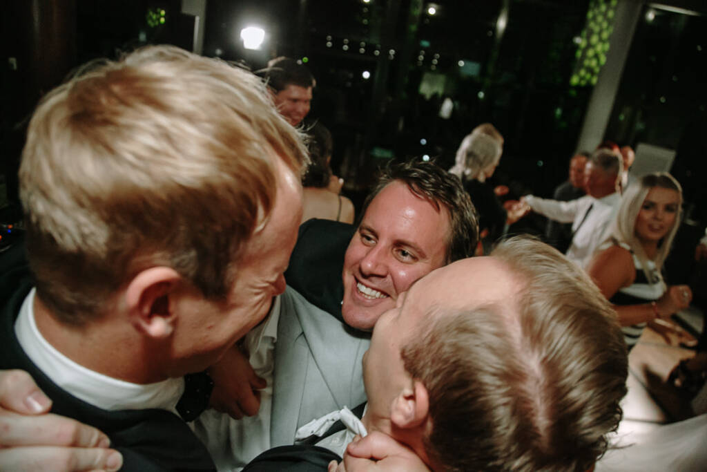 Nick smiles in a group hug with two guests on The National's dance floor.
