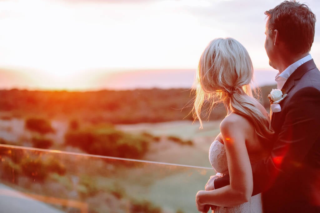 Nick holds Aasher beside The National's glass terrace balustrade at sunset over the Mornington Peninsula links.