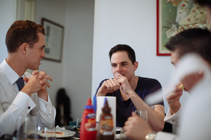 Three men sit around a table during wedding preparations.