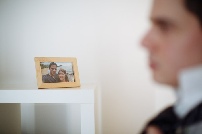 A framed waterfront photograph sits on a shelf during wedding preparations.