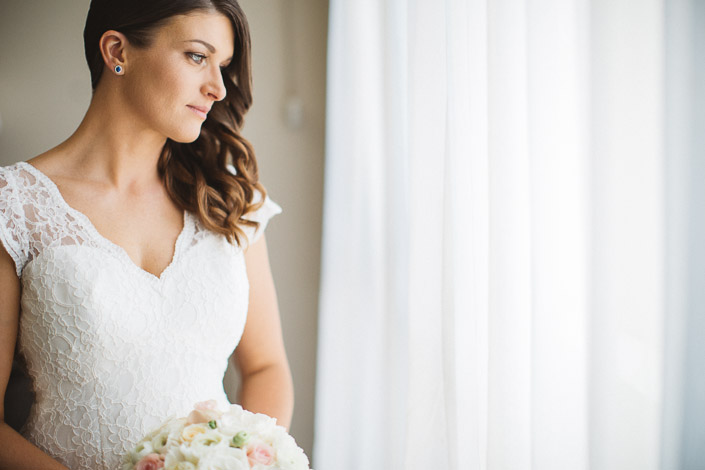 Pascale holds her bouquet beside sheer curtains at Quest on William.