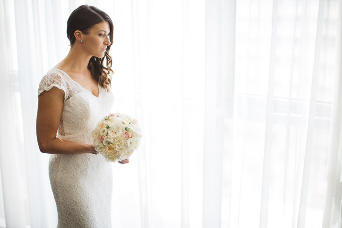 Pascale holds a pale rose bouquet beside the window at Quest on William.