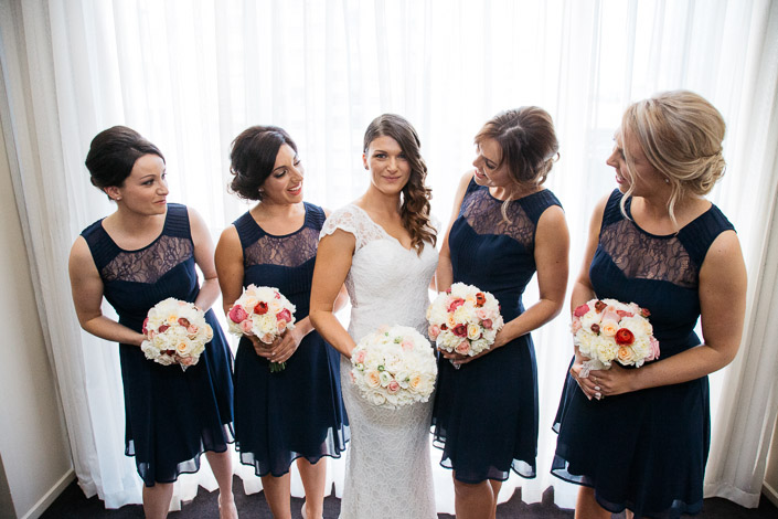 Navy lace bridesmaids close around the bride and her white posy