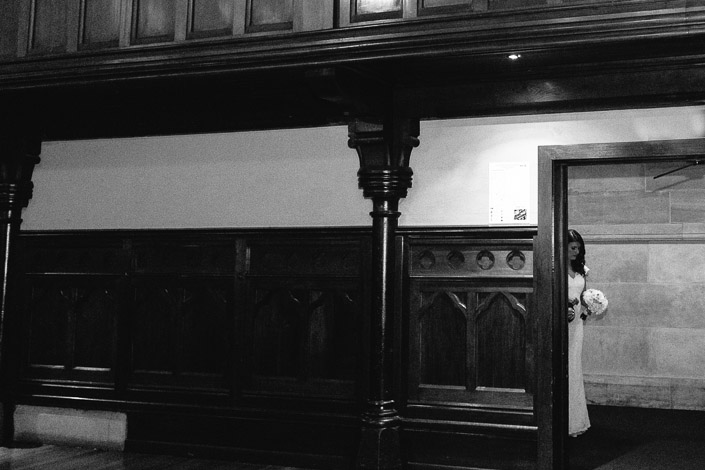 Black-and-white portrait of Pascale beside carved timber panelling in the heritage hall at The Chapter House.