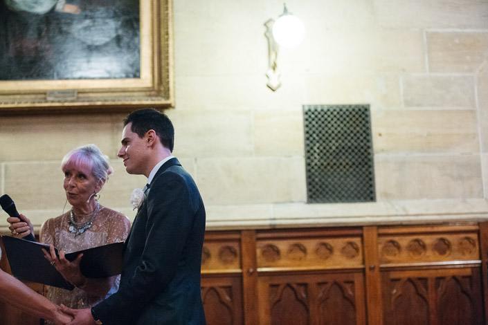 The celebrant holds a microphone beside the groom at Chapter House.