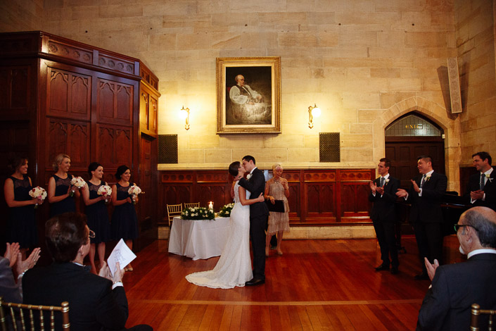 Pascale and Pasquale kiss as their wedding party applauds at The Chapter House.