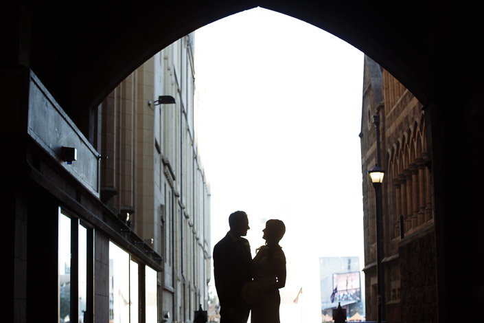 Pascale and Pasquale appear in silhouette beneath the stone arch beside The Chapter House.