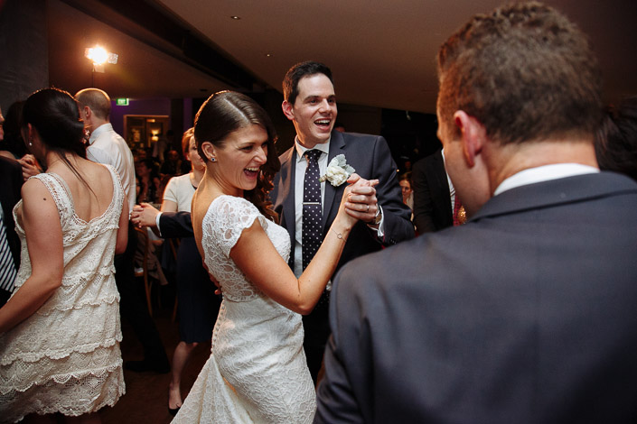 Pascale and Pasquale laugh while dancing among their wedding guests.