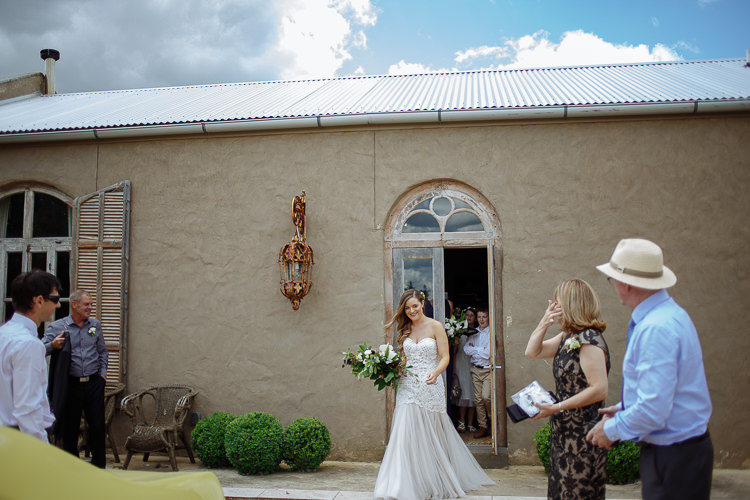 Stepping out of the arched door with her bouquet, Elysha is met by a woman gasping.