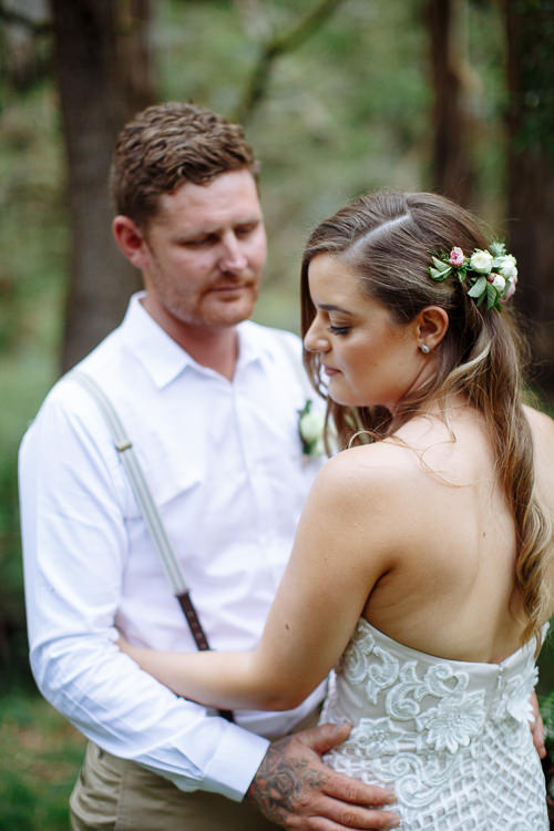 Mitch's tattooed hand rests at Elysha's waist as she looks down, beaded bodice in frame.