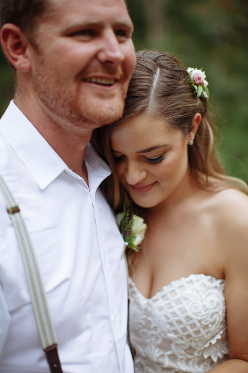 Resting her head on Mitch's chest with eyes down, Elysha smiles as he laughs.