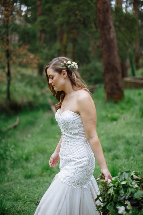 Profile of Elysha in the forest clearing, roses pinned in her hair, bouquet at her hip.