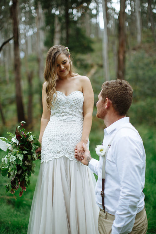 Kneeling and holding Elysha's hand, Mitch is smiled at from above among pale gum trunks.