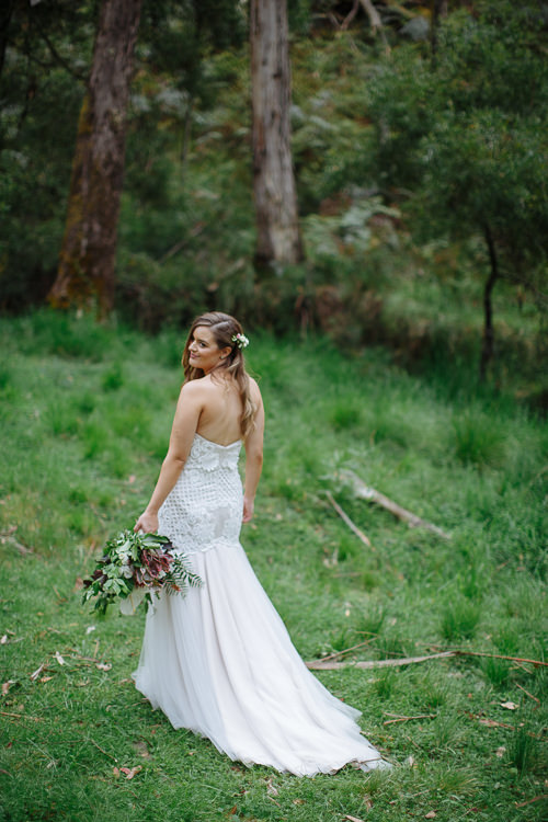 Glancing over her shoulder, Elysha shows the low back of the gown, train on the grass.