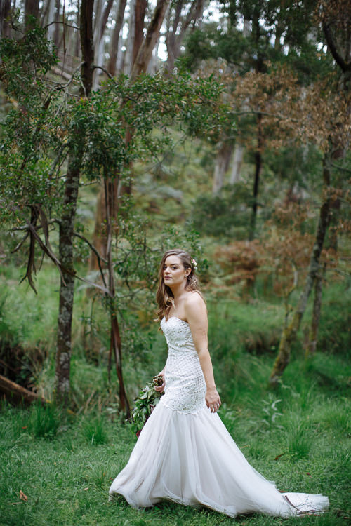 Walking through long grass beneath a lichen covered gum, Elysha looks off to the right.