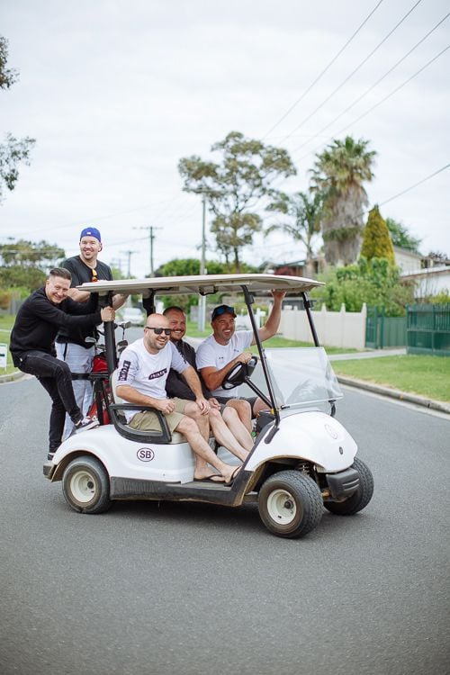 Groomsmen piling onto a golf cart for a wedding-morning round of golf