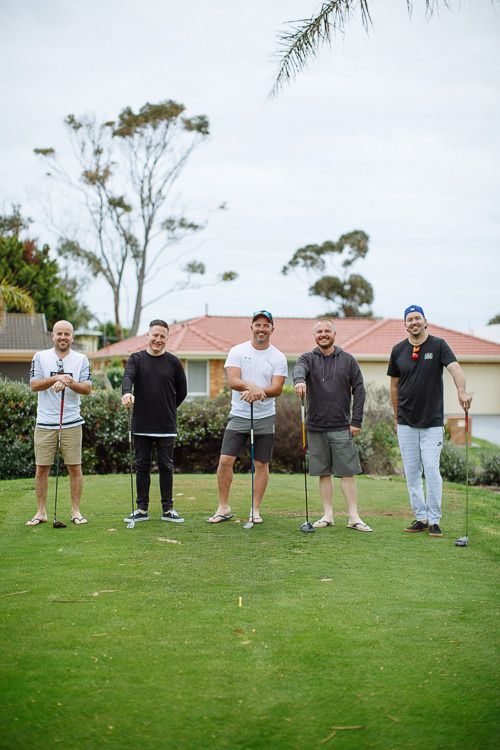 Groomsmen lined up with their drivers on the tee before the wedding