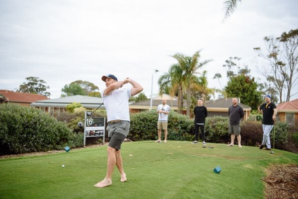 Groom teeing off during a relaxed wedding-morning golf game